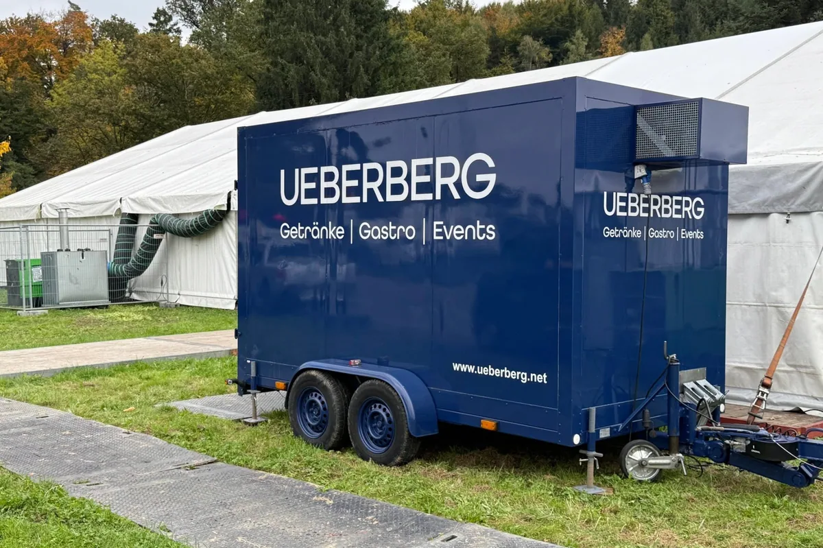 Blauer Ueberberg Kühlanhänger neben einem Veranstaltungszelt
